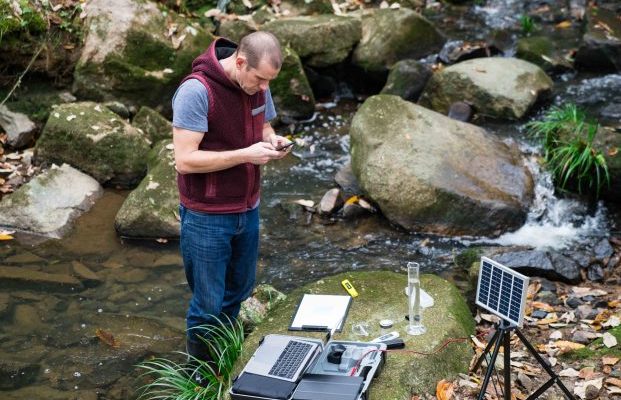 A scientist monitoring water quality from a solar powered field laboratory